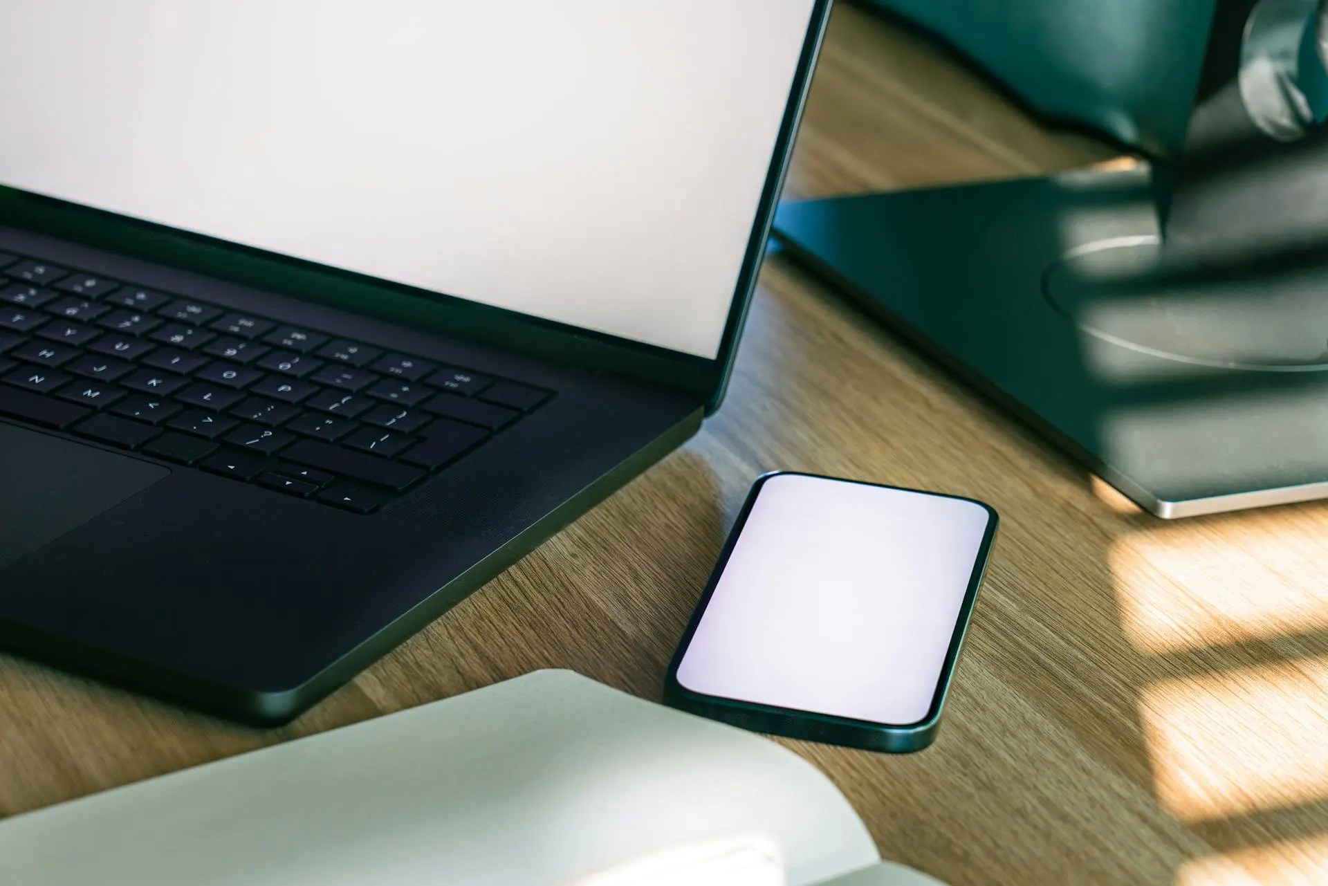 Posto de trabalho com portátil e smartphone numa secretária organizada.