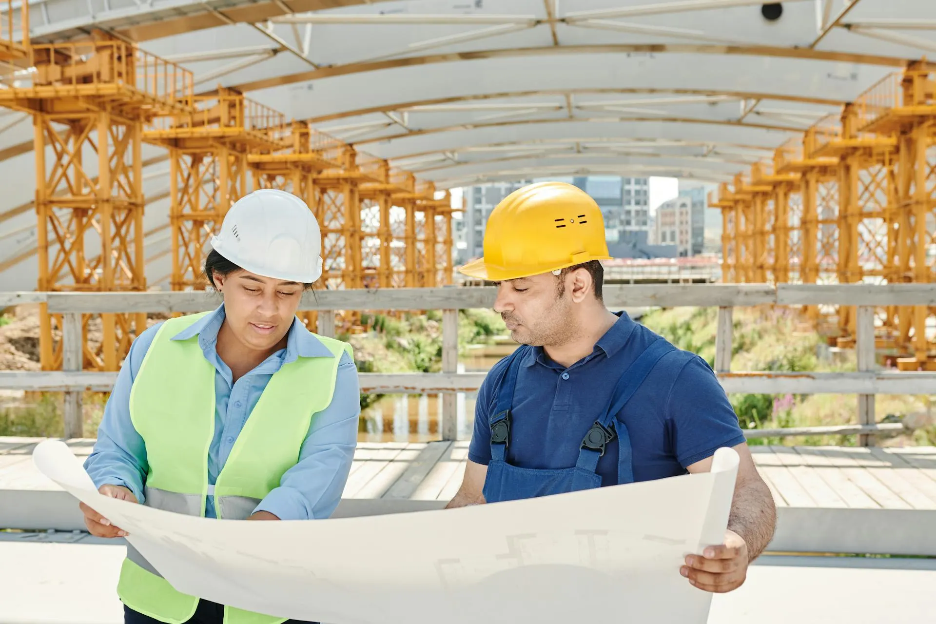 Equipa de engenharia a analisar plantas técnicas num estaleiro de obra.